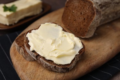 Slices of tasty bread with butter on wooden board, closeup