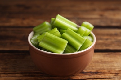 Photo of Cut celery in bowl on wooden table