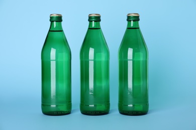 Photo of Glass bottles with water on light blue background