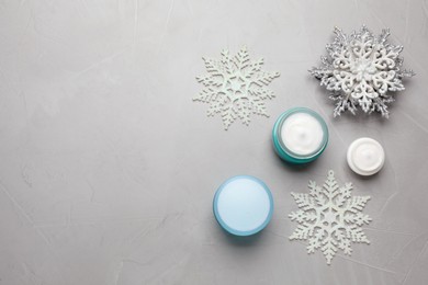 Photo of Flat lay composition with cosmetic products and snowflakes on light grey table, space for text. Winter skin care