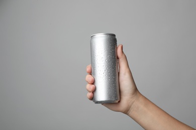 Photo of Woman holding aluminum can with beverage on grey background, closeup. Space for design