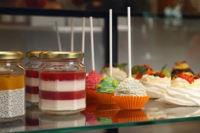 Photo of Showcase with different tasty desserts in store, closeup