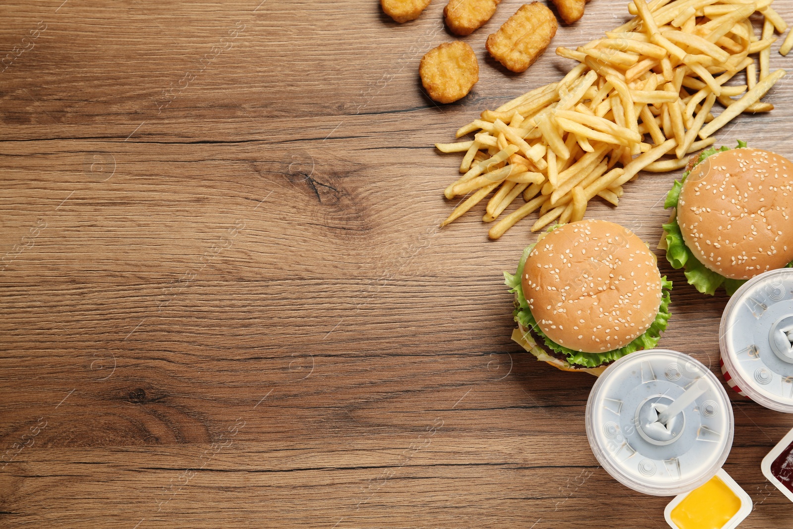 Photo of Flat lay composition with delicious fast food menu on wooden table. Space for text