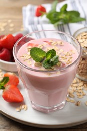 Photo of Glass of tasty berry smoothie with oatmeal on plate, closeup