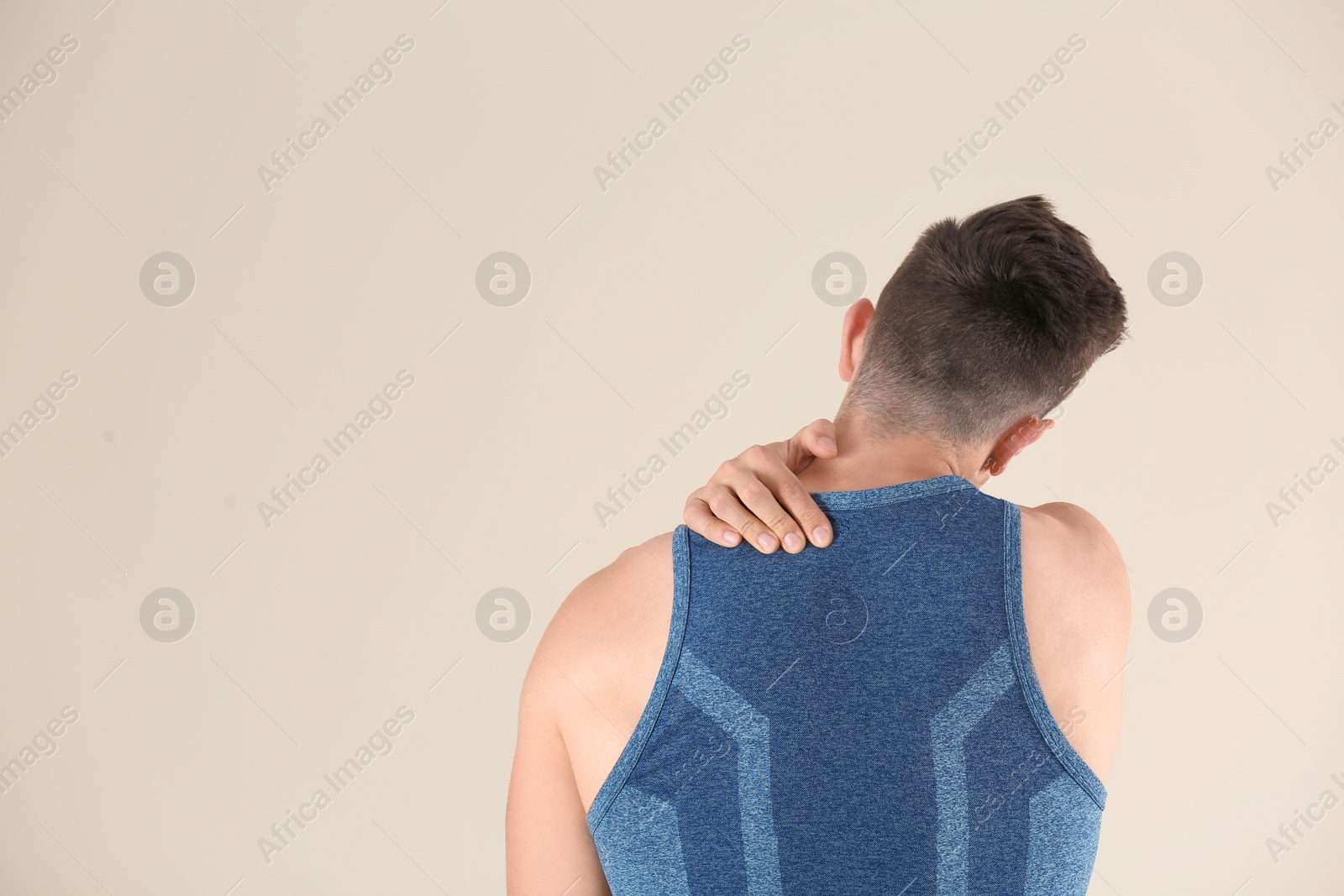 Photo of Man in sportswear suffering from back pain on light background