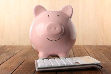 Calculator and piggy bank on wooden table