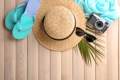 Flat lay composition with stylish hat, camera and beach objects on wooden background