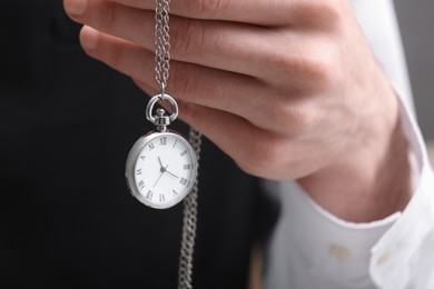 Photo of Man holding chain with elegant pocket watch, closeup