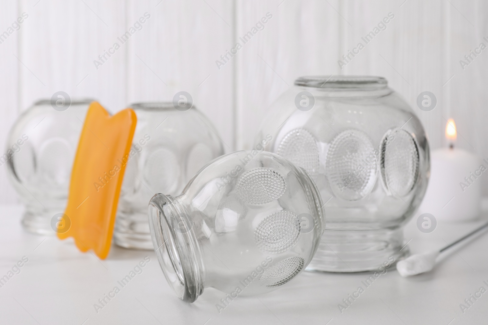 Photo of Glass cups and gua sha on white table, closeup. Cupping therapy