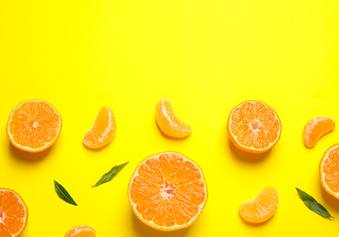 Photo of Flat lay composition with halves of fresh ripe tangerines and leaves on yellow background, space for text. Citrus fruit