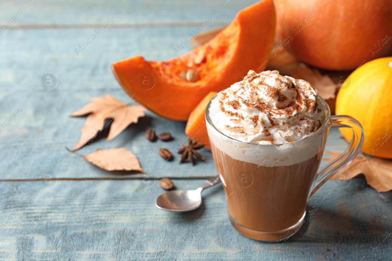 Photo of Glass cup with tasty pumpkin spice latte and space for text on wooden table