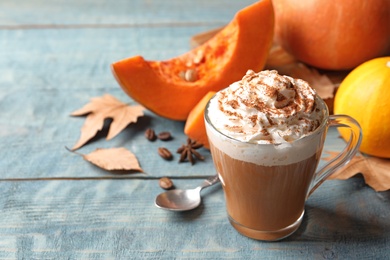 Photo of Glass cup with tasty pumpkin spice latte and space for text on wooden table