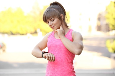 Young woman checking pulse after workout in park