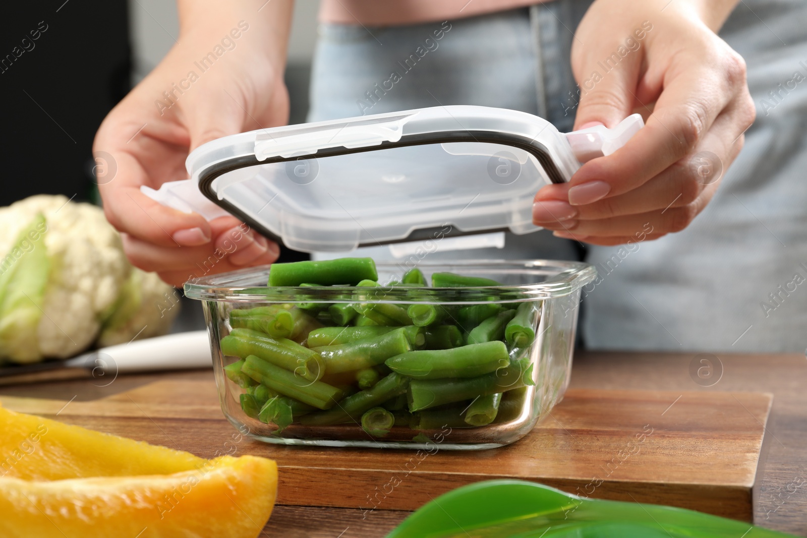 Photo of Woman closing container with lid at table, closeup. Food storage