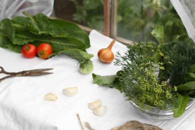Photo of Fresh green herbs, tomatoes, garlic cloves and onion on table indoors