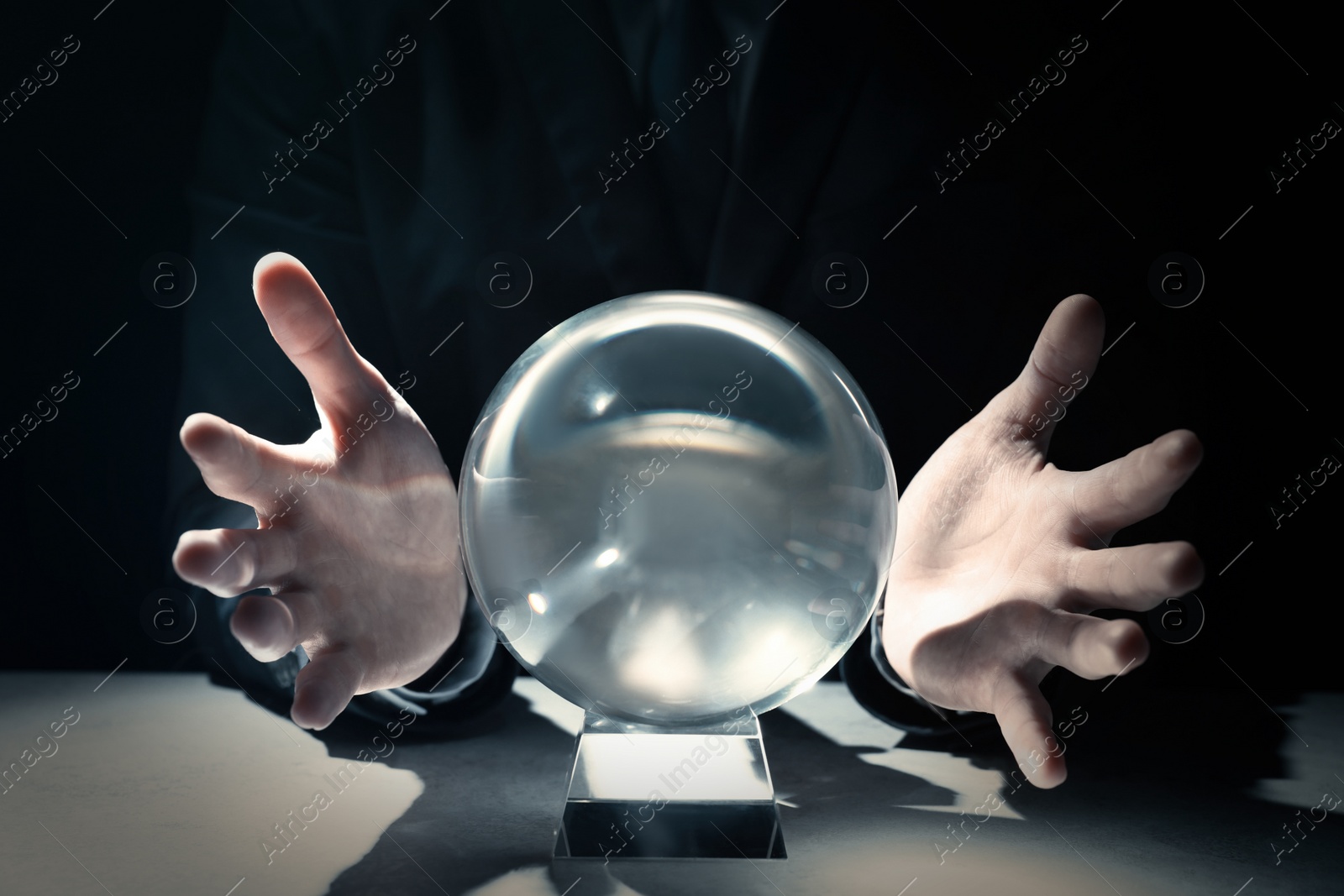 Photo of Businessman using crystal ball to predict future at table in darkness, closeup