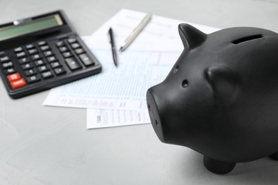 Photo of Black piggy bank, documents and calculator on table