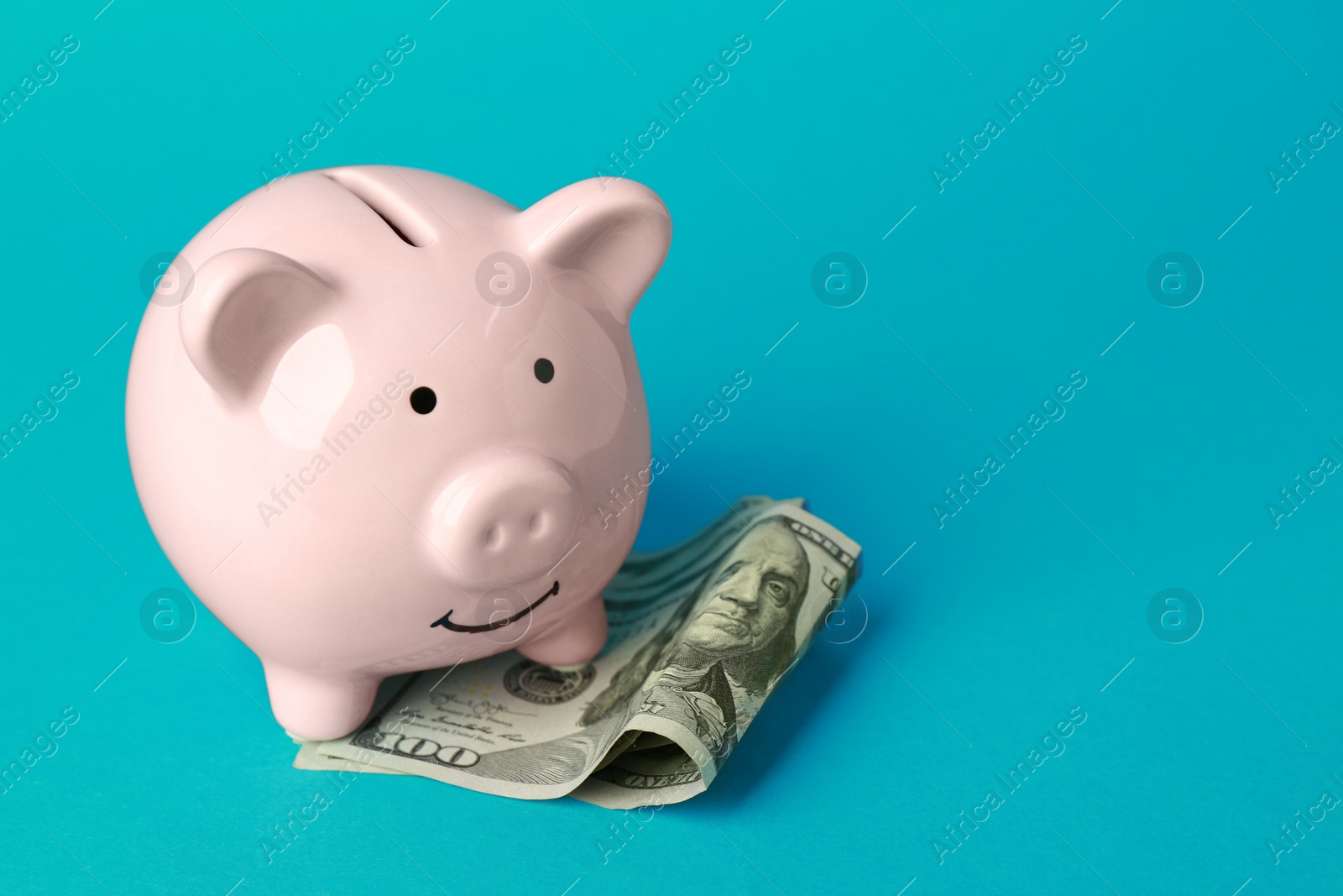 Photo of Ceramic piggy bank and banknotes on turquoise background. Space for text