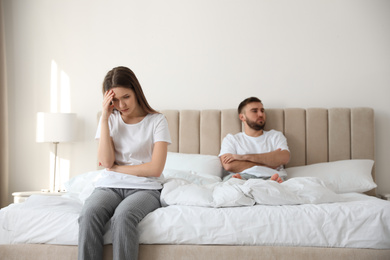 Photo of Unhappy couple with problems in relationship on bed at home