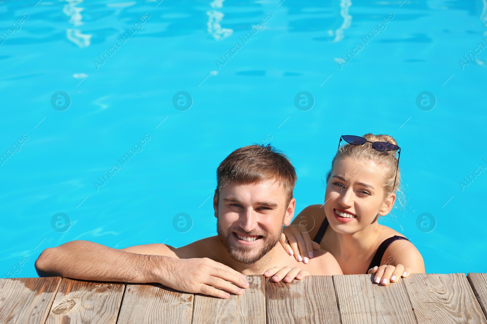 Photo of Happy young couple in swimming pool at resort