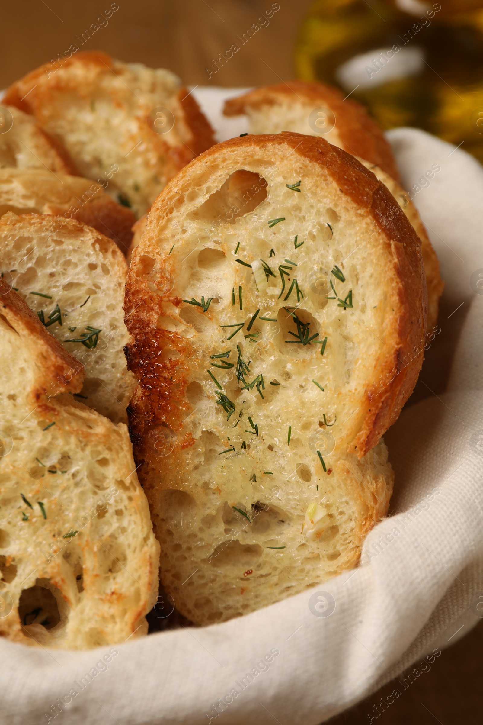 Photo of Tasty baguette with garlic and dill in basket, closeup