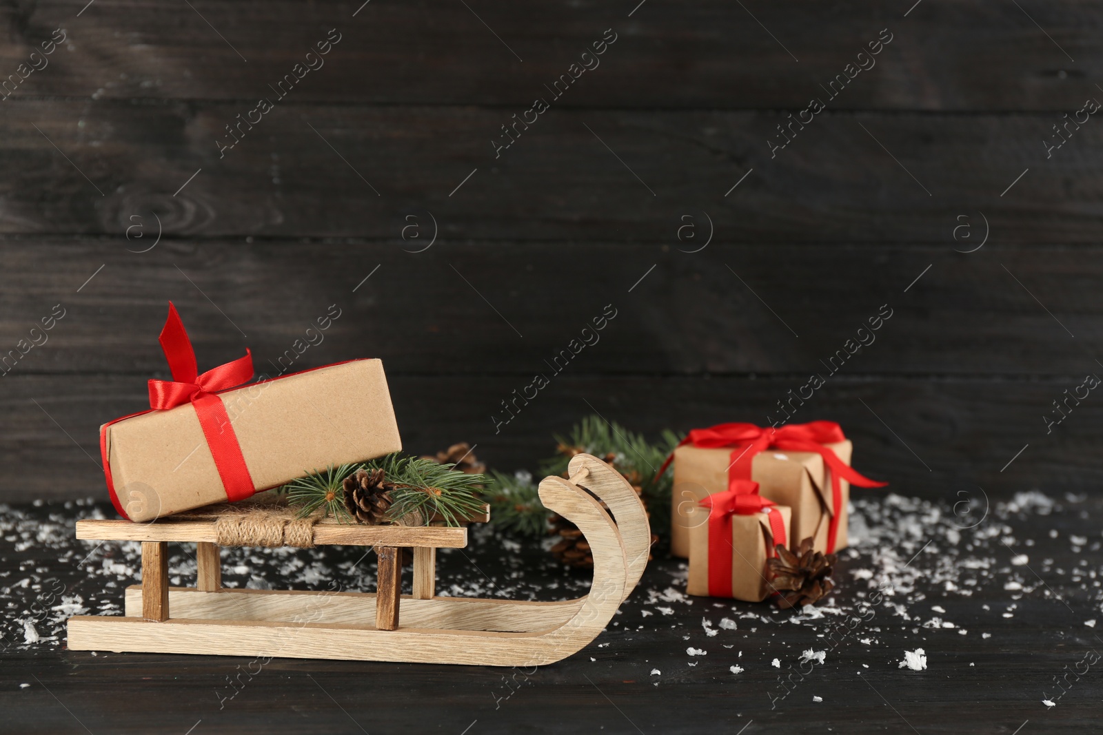Photo of Beautiful Christmas composition with miniature sleigh on black wooden table. Space for text