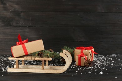 Beautiful Christmas composition with miniature sleigh on black wooden table. Space for text