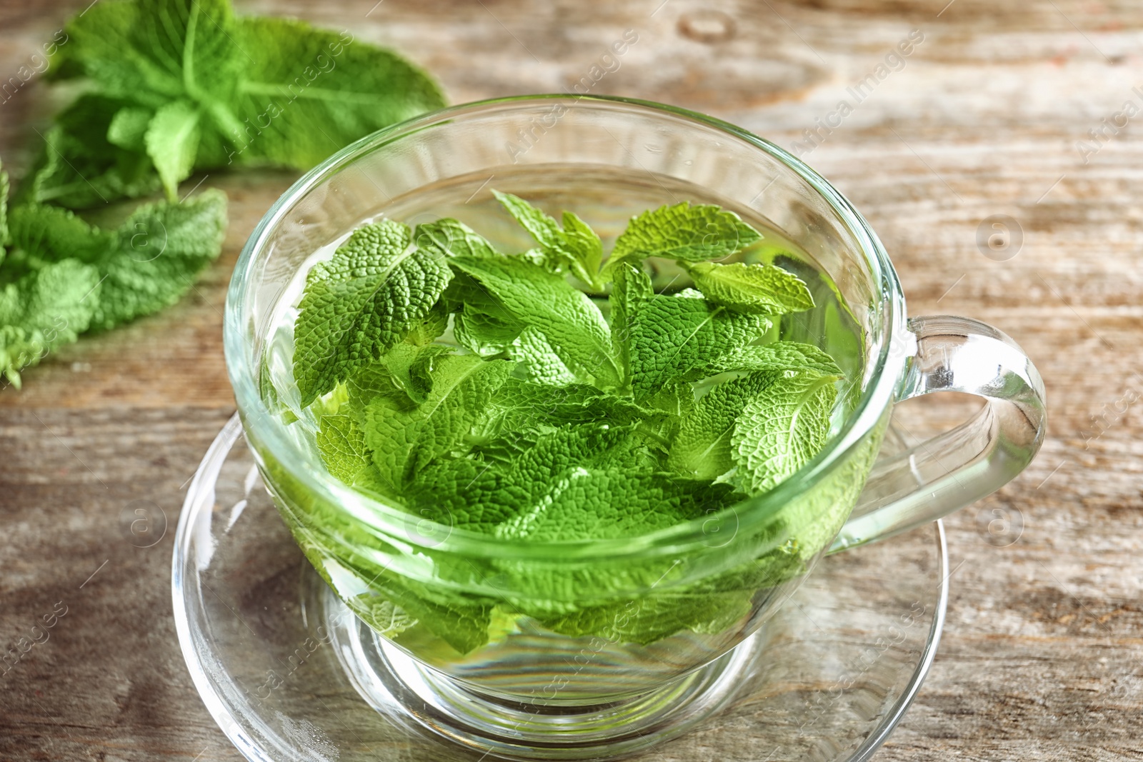 Photo of Cup with hot aromatic mint tea on wooden table