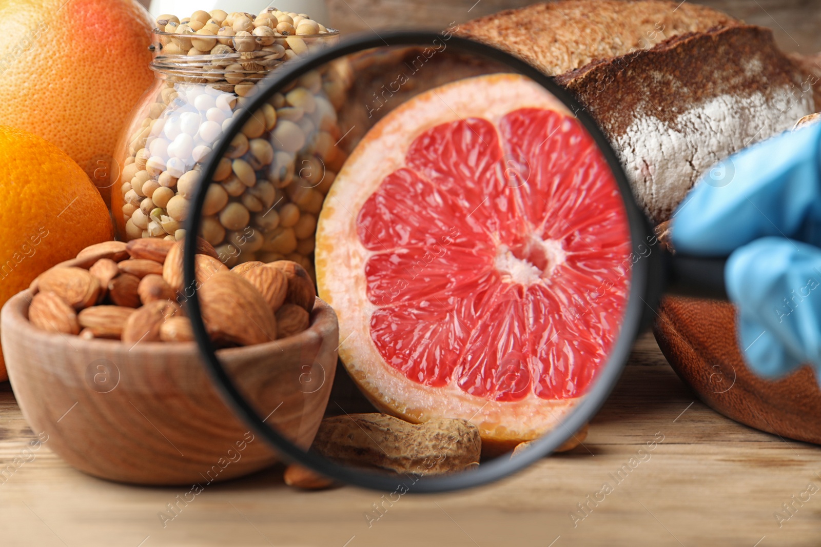 Photo of Different products with magnifier focused on grapefruit, closeup. Food allergy concept
