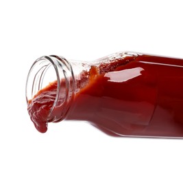 Pouring tasty red ketchup from glass bottle isolated on white