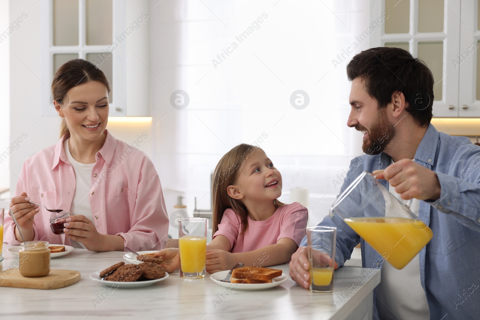 Photo of Happy family having breakfast at table in kitchen