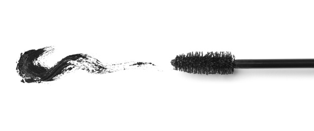 Photo of Applicator and black mascara smear for eyelashes on white background, top view