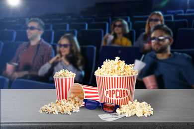 Image of Popcorn, 3D glasses, tickets on table and young people in cinema hall