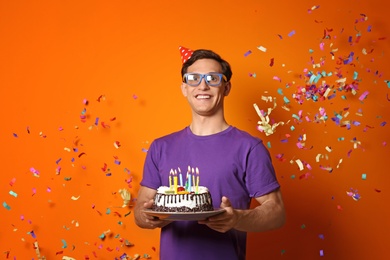 Photo of Young man with birthday cake on color background