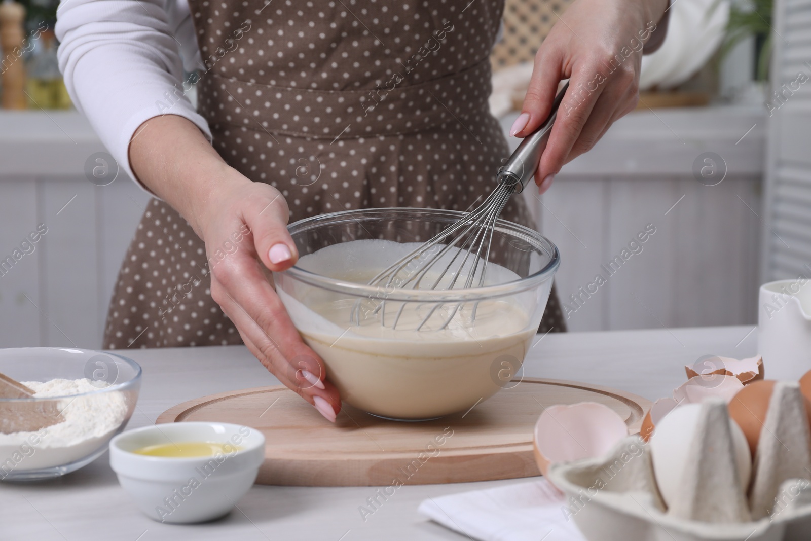 Photo of Woman making dough with whisk in bowl at table, closeup