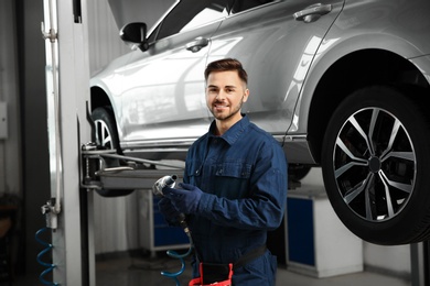Photo of Technician with tool in automobile repair shop