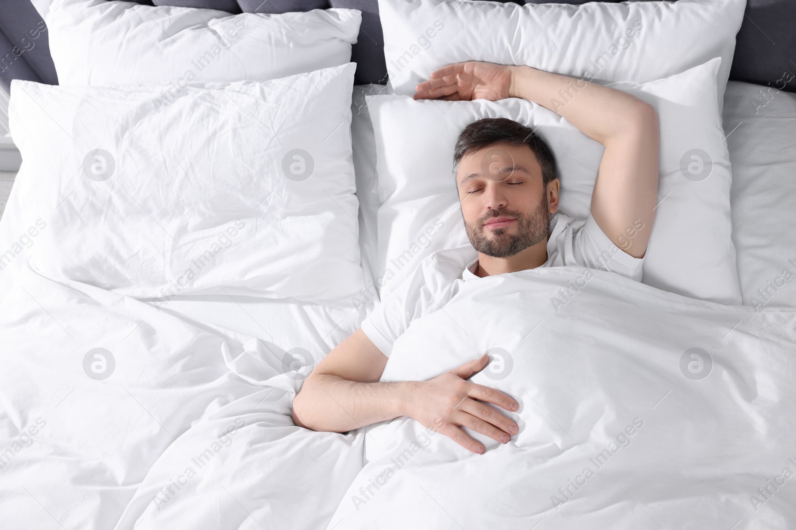 Photo of Handsome man sleeping in soft bed, top view