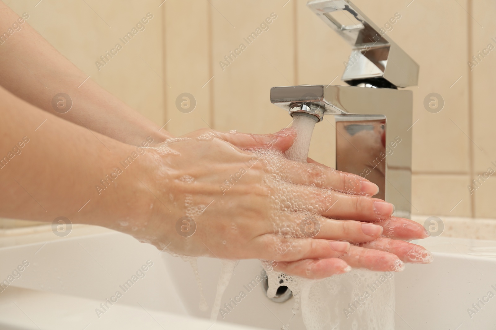 Photo of Woman washing hands with antiseptic soap in bathroom, closeup