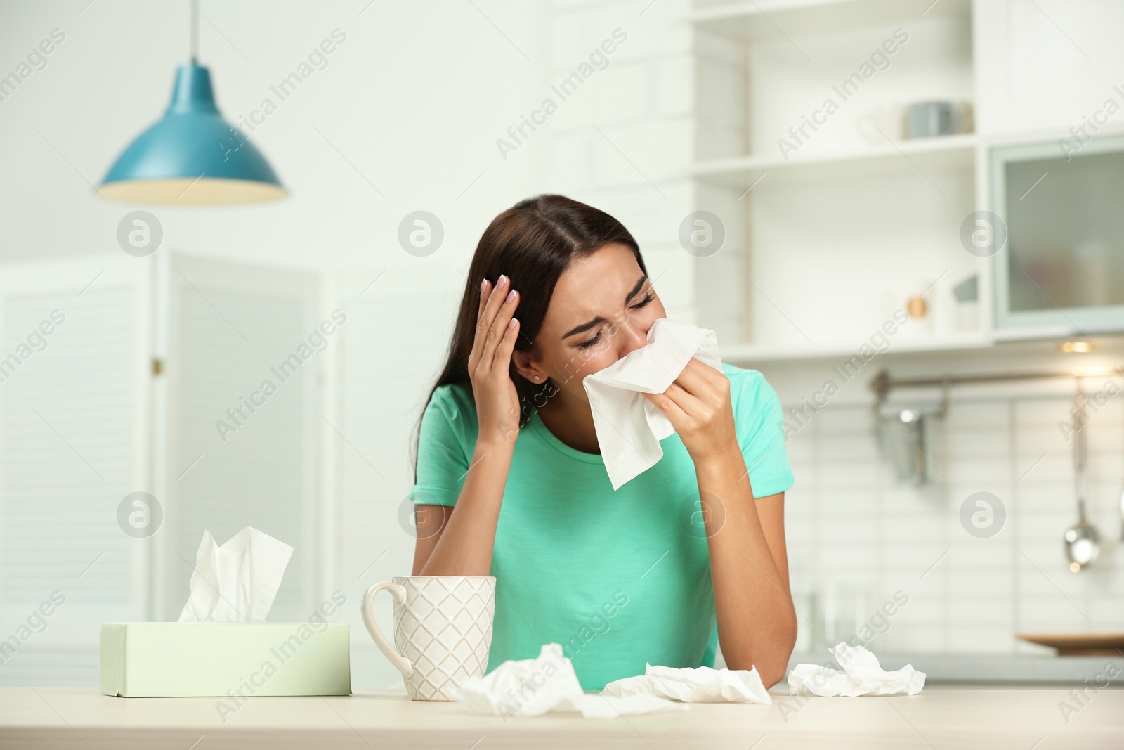 Photo of Young woman suffering from allergy in kitchen