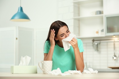 Photo of Young woman suffering from allergy in kitchen