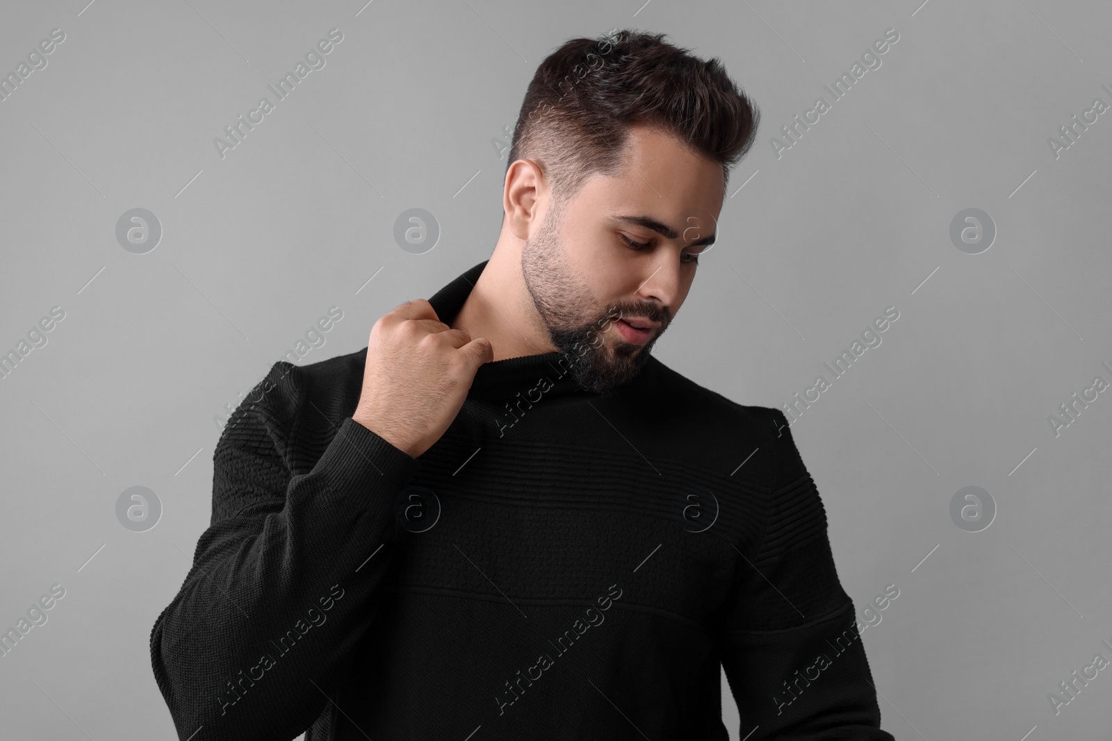 Photo of Handsome man in stylish black sweater on grey background