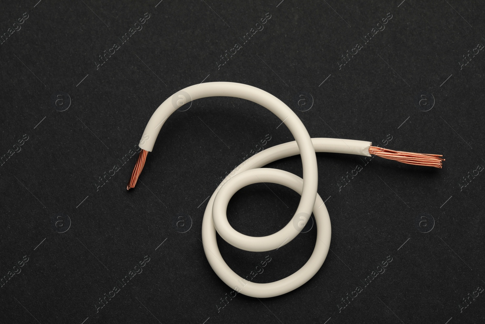 Photo of Piece of white electrical wire on black background, top view