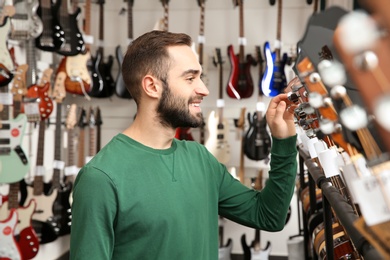 Buyer choosing guitar in modern music store