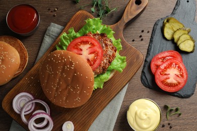 Photo of Delicious burger with beef patty and ingredients on wooden table, flat lay