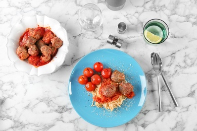 Photo of Delicious pasta with meatballs and tomato sauce on light background, flat lay