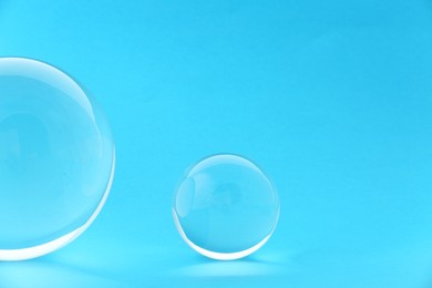 Photo of Transparent glass balls on light blue background. Space for text