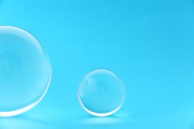 Transparent glass balls on light blue background. Space for text