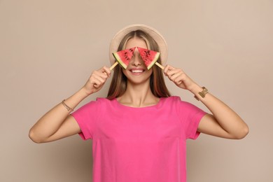 Beautiful girl with pieces of watermelon on beige background