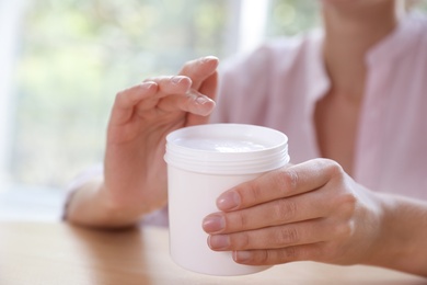 Photo of Woman with jar of moisturizing cream, closeup