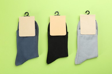 Photo of Soft cotton socks on light green background, flat lay